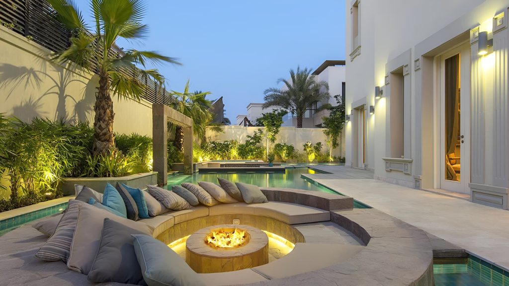 A luxury villa terrace in Dubai featuring a rooftop garden with lounge seating, ambient lighting, and modern landscaping elements like raised planters and pergolas.